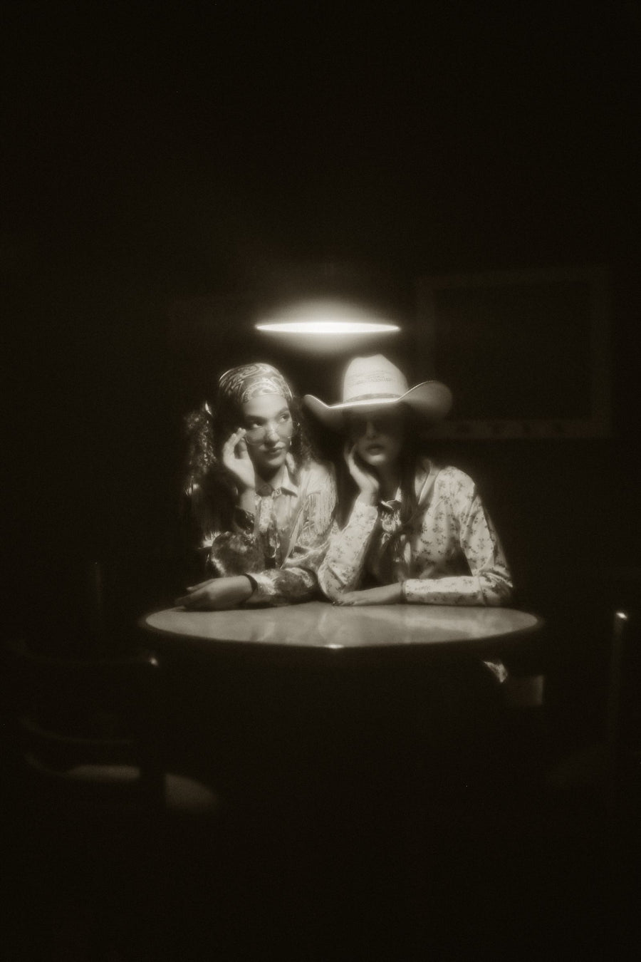 Sombrero de ala ancha y abrigo de pelo en penumbra, junto a la mesa de billar
